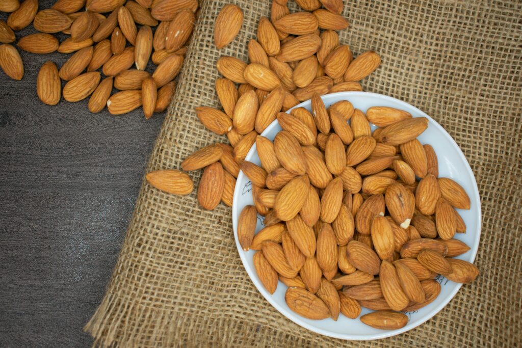 A top-down image of a bunch of roasted almonds in a bowl as an example of a healthy fat choice.
