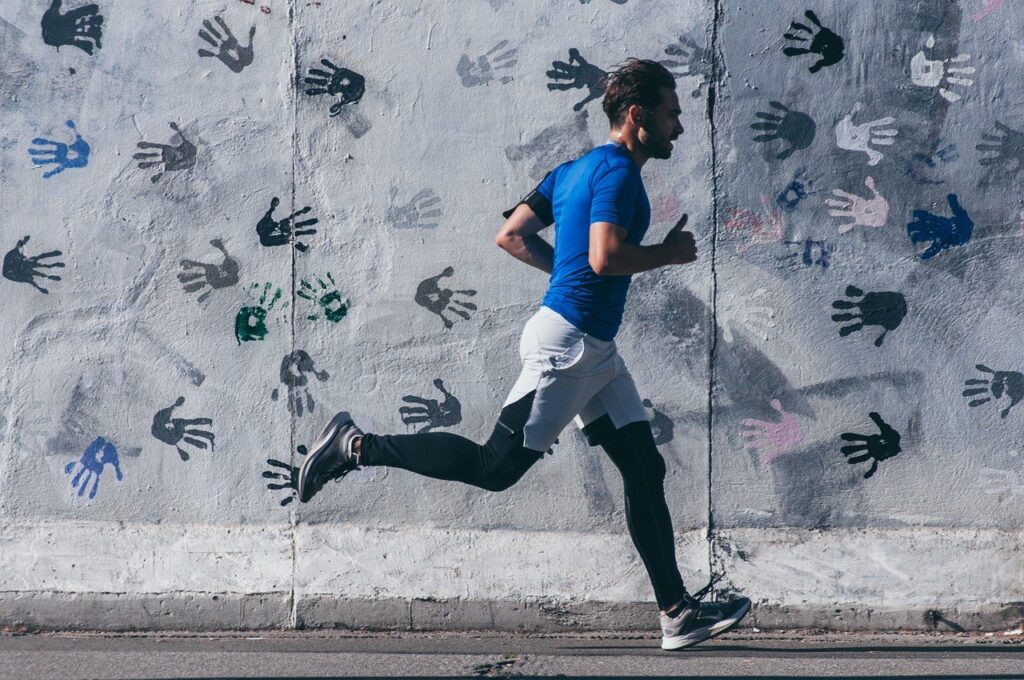 A man running along a grey wall.