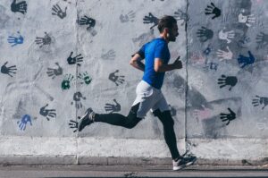A man running along a grey wall.