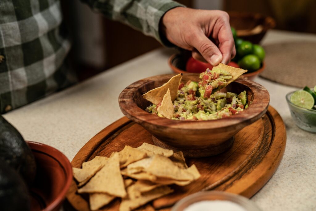 An image of someone dipping a tortilla chip into a homemade salsa.