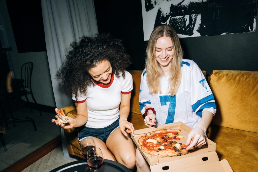 Two friends enjoy a pizza and a glass of wine together.