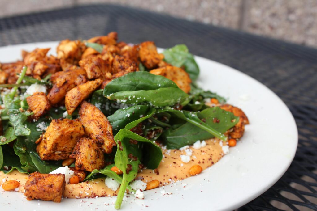 A plate of chicken and spinach over a bed of sweet potato.