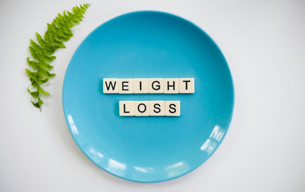 A blue plate with the words "weight loss" written on it in white and black tiles.