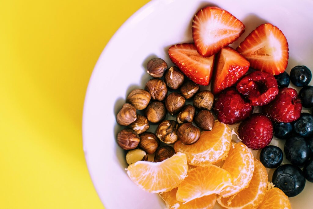How-to-Start-a-Plant-Based-Diet-The-Beginner's-Guide-Supporting A picture of a plate filled with colourful fruit and hazelnuts.