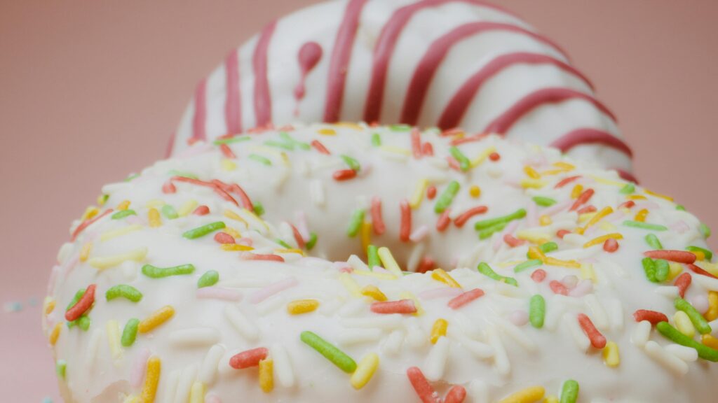 An image of a couple of donuts with icing and sprinkles on top.