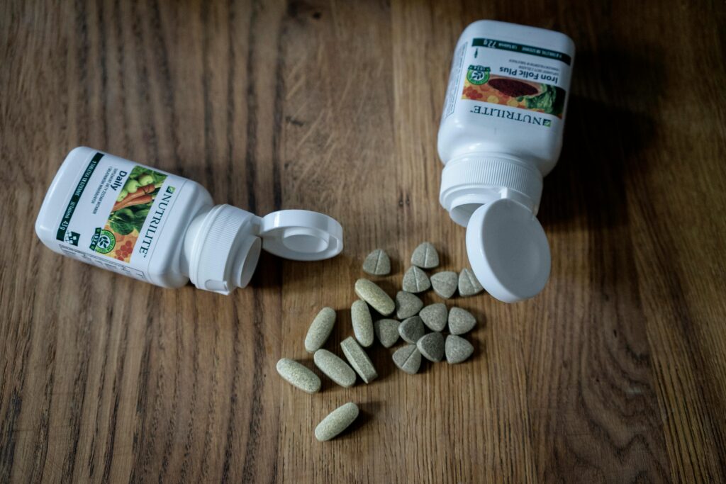 An image of a vegan supplement bottle on it's side with some of the pills on the table.