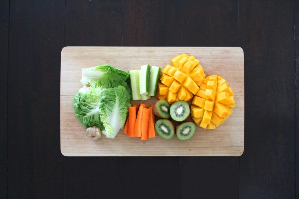 A top-down image of a cutting board with colourful fruits and veggies that are naturally vegan.
